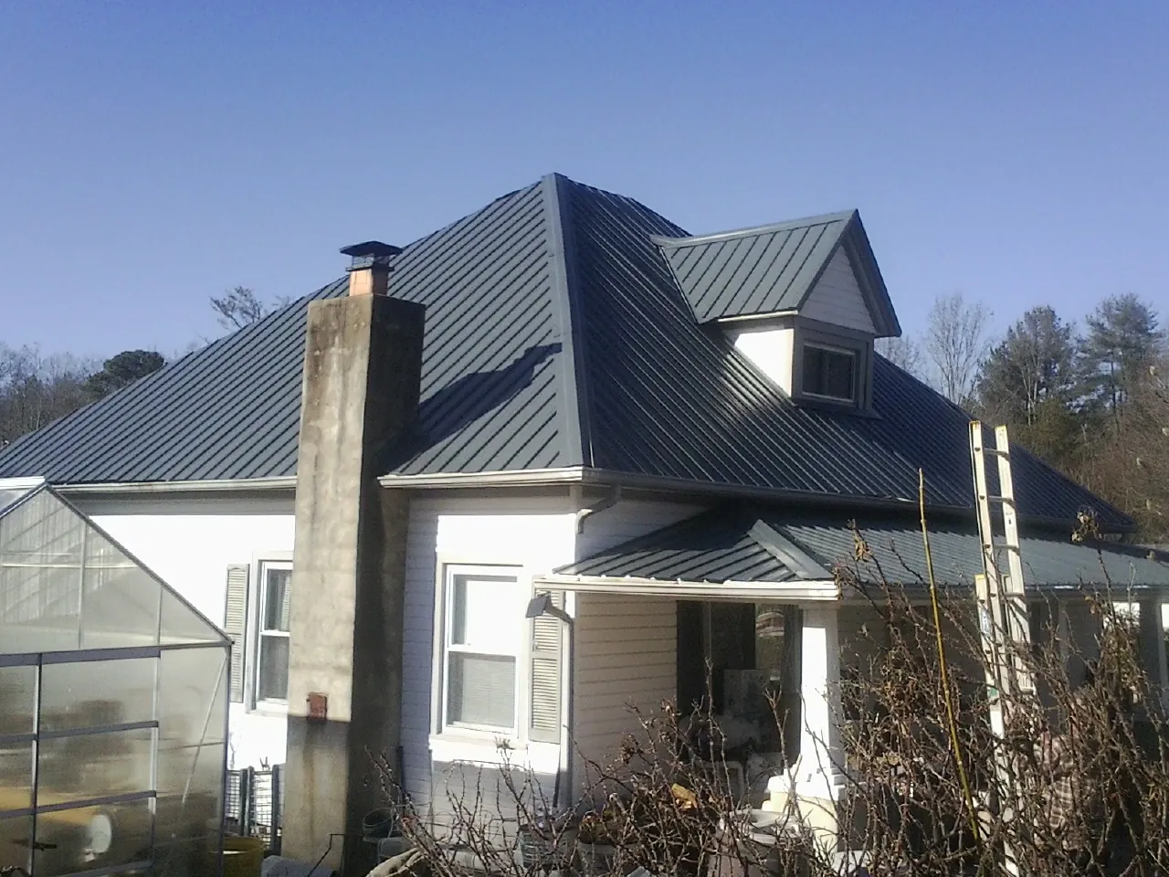 Dark blue standing seam metal roof on a white farmhouse with dormer — Slate & Tile Roof Repair by Roofing Brothers in Rayne