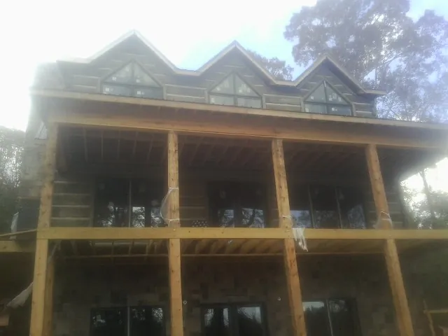 Dormers and porch framing on a large log home under construction — Roof Coating work by our crew in Rayne