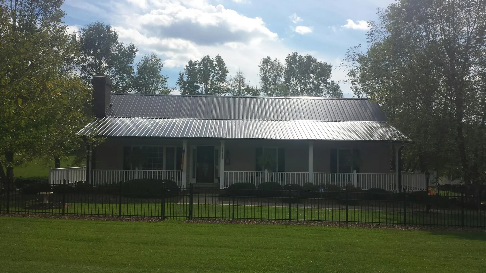 Gray metal roof on a brick ranch with a full width front porch — Gutter Guard Installation work by our crew in Rayne