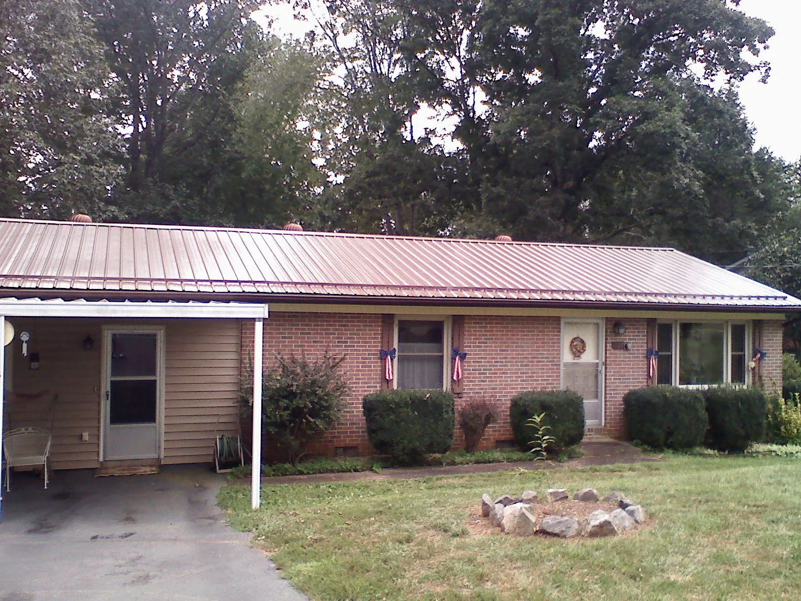 Bronze metal roof and carport on a brick ranch home — Roof Repair work by our crew in Rayne
