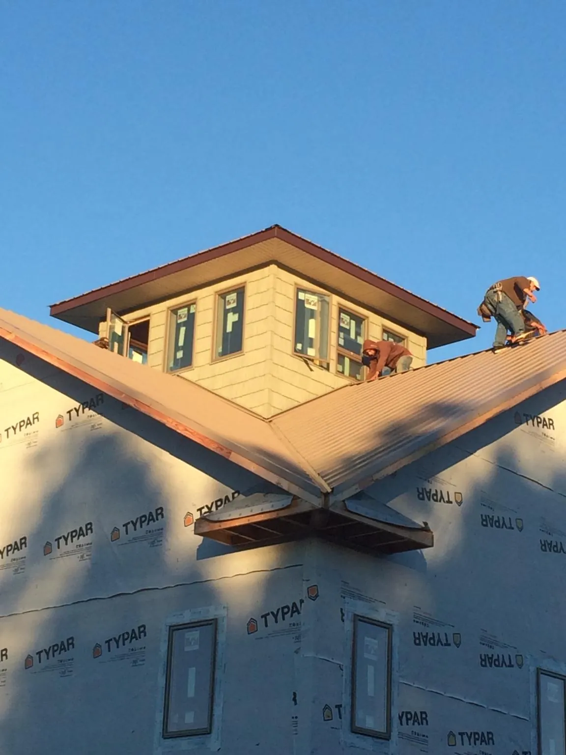Roofers working around a rooftop cupola on a new metal roof at sunset — Roof Waterproofing in Rayne by Roofing Brothers